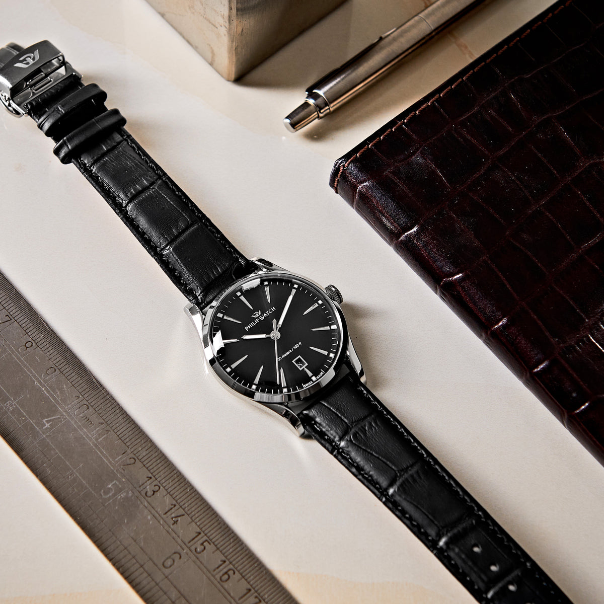 Philip Watch Sunray R8251180036 ambientato su scrivania, con quadrante nero e cinturino in pelle